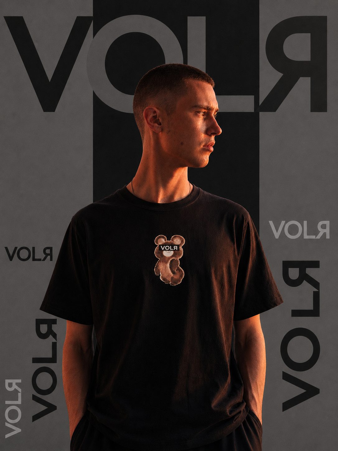 VOLЯ Kampagnenmotiv: Person im schwarzen Mischka T-Shirt vor einer Wand mit VOLЯ-Schriftzügen